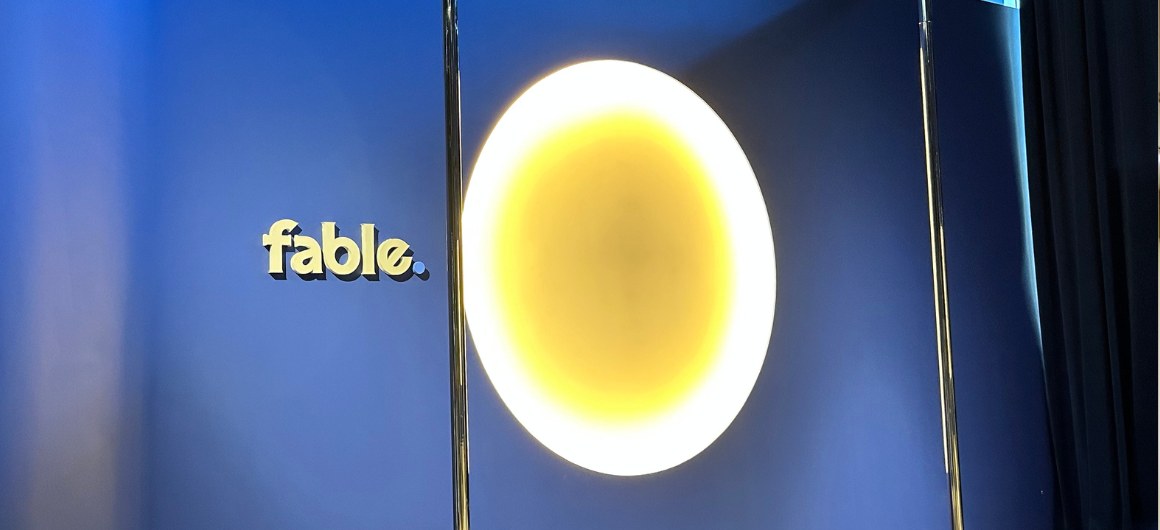 Navy blue feature wall with a glowing circular light and gold logo, Fable dance studio